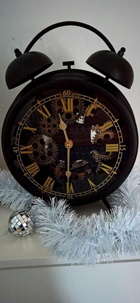 Ein schwarzer altertümlicher Wecker mit römischen Ziffern und Zahnrädern in seinem Inneren